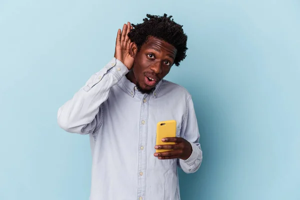 年轻的非洲裔美国人 手持蓝色背景的手机 试图听闲话 — 图库照片