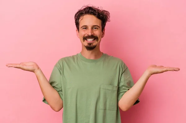 Young Caucasian Man Isolated Pink Background Makes Scale Arms Feels — Stock Photo, Image
