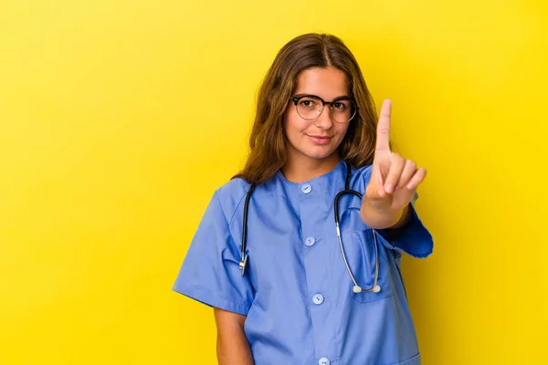 Sarı Arka Planda Izole Edilmiş Genç Hemşire Bir Numarayı Parmağıyla — Stok fotoğraf