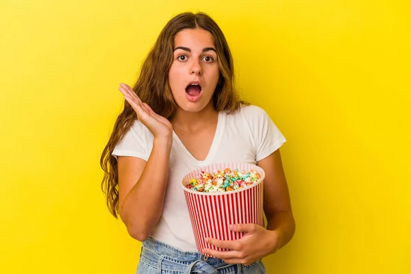 Jovem Caucasiana Segurando Uma Pipoca Isolada Fundo Amarelo Surpreso Chocado — Fotografia de Stock