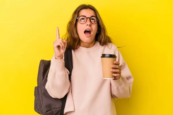 若いですCaucasian学生女性保持コーヒー孤立上の黄色の背景ポインティングアップでオープン口 — ストック写真