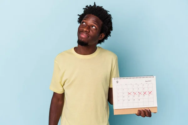 Jonge Afro Amerikaanse Man Houdt Kalender Geïsoleerd Blauwe Achtergrond Dromen — Stockfoto