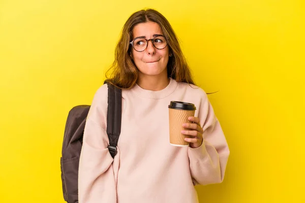Jovem Estudante Caucasiano Segurando Café Isolado Fundo Amarelo Confuso Sente — Fotografia de Stock