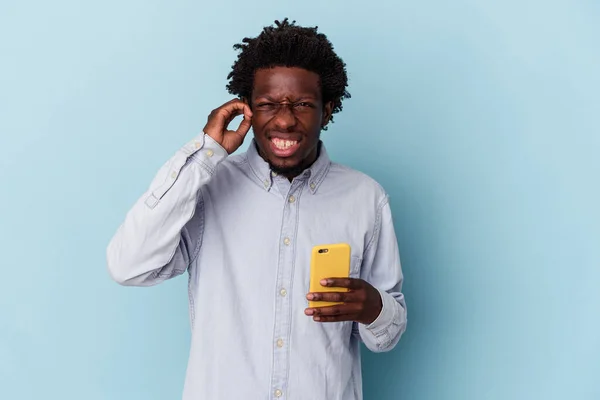 年轻的非洲裔美国人 手持蓝色背景的手机 用手捂住耳朵 — 图库照片