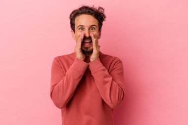 Pembe arka planda izole edilmiş genç beyaz bir adam bir dedikodu söylüyor, bir haber sunuyor..