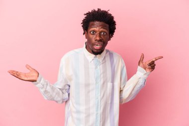 Genç Afrikalı Amerikalı bir adam pembe arka planda izole edilmiş ve elinde bir ürün tutuyor..