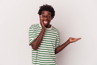 Beyaz arka planda izole edilmiş genç Afro-Amerikalı bir adam avuç içinde fotokopi alanı tutuyor, el üstünde tutuyor. Şaşırmış ve mutlu..