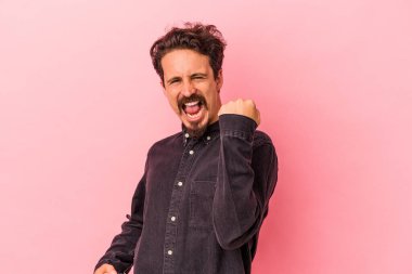 Pembe arka planda soyutlanmış, tasasız ve heyecanlı genç bir beyaz adam. Zafer konsepti.