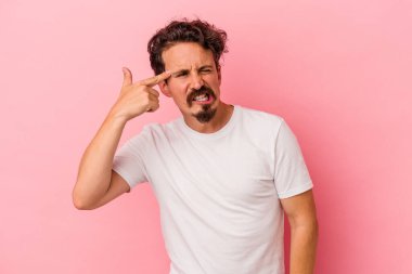 Pembe arka planda izole edilmiş genç beyaz adam kulaklarını elleriyle kapatıyor..