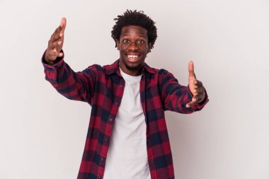 Genç Afrikalı Amerikalı bir adam beyaz arka planda izole edilmiş zaferi ya da başarıyı kutluyor, şaşırmış ve şok olmuş..
