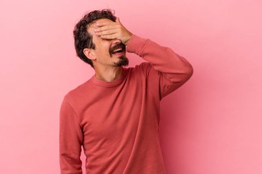 Pembe arka planda izole edilmiş genç beyaz adam ellerini başının üstünde tutarak neşeyle gülüyor. Mutluluk kavramı.