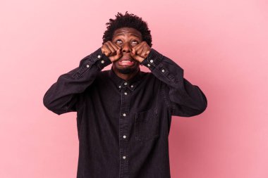Genç Afro-Amerikalı adam pembe arka planda yalnız başına sızlanıyor ve ağlıyordu..