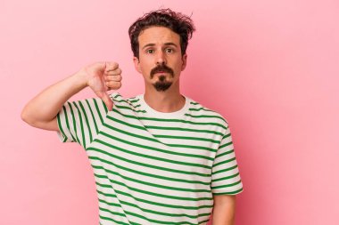 Pembe arka planda izole edilmiş genç beyaz bir adam hoş olmayan bir jest yapıyor. Anlaşmazlık konsepti.