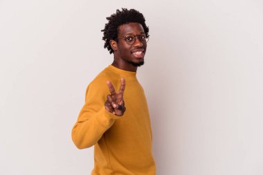 Beyaz arka planda izole edilmiş genç bir Afrikalı Amerikalı zafer işareti gösteriyor ve gülümsüyor..