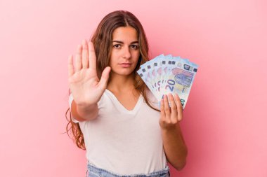 Elinde pembe arka planda izole edilmiş banknotlar tutan beyaz bir kadın elini uzatıp dur işareti göstererek seni engelliyor..