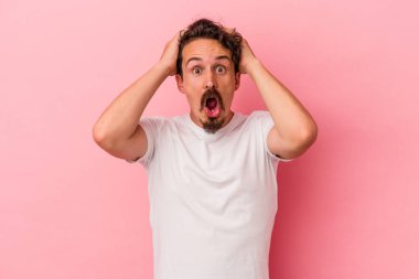 Pembe arka planda izole edilmiş genç beyaz adam şaşırdı ve şok oldu..