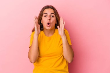 Pembe arka planda izole edilmiş genç beyaz kadın şaşırmış ve şok olmuş..