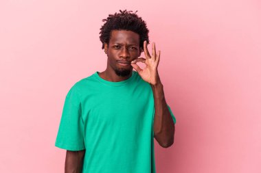 Genç Afrikalı Amerikalı, pembe arka planda izole edilmiş, parmakları dudaklarında bir sır saklıyor..