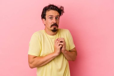 Pembe arka planda izole edilmiş genç beyaz adam korkmuş ve korkmuş..