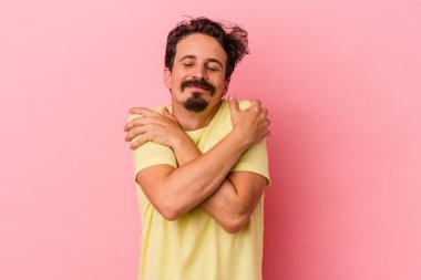 Kafkasyalı genç adam pembe arka planda izole edilmiş, güler yüzlü, kaygısız ve mutlu..
