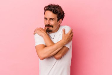 Kafkasyalı genç adam pembe arka planda izole edilmiş, güler yüzlü, kaygısız ve mutlu..