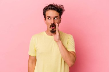 Pembe arka planda izole edilmiş genç beyaz adam gizli bir sıcak fren haberi veriyor ve yana bakıyor.