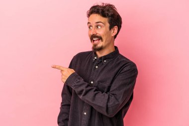 Pembe arka planda soyutlanmış genç beyaz bir adam gülümsüyor, neşeli ve keyifli görünüyor..