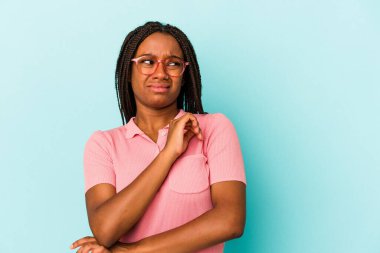 Genç Afrikalı Amerikalı kadın mavi arka planda izole edilmiş kafası karışmış, şüpheli ve güvensiz hissediyor..