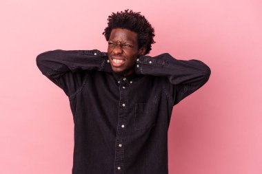Genç Afro-Amerikan erkek, pembe arka planda izole edilmiş, sabit yaşam tarzından dolayı boyun ağrısı çekiyor..