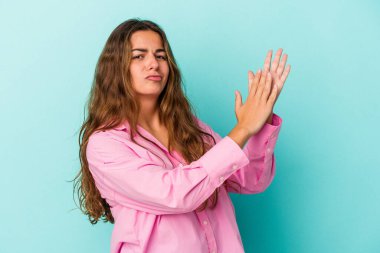 Mavi arka planda izole edilmiş genç beyaz kadın enerjik ve rahat hissediyor, ellerini ovuşturuyor..