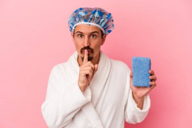 Beyaz bir genç, elinde süngerle duşa giriyor. Pembe arka planda ya sır saklıyor ya da sessizlik istiyor..