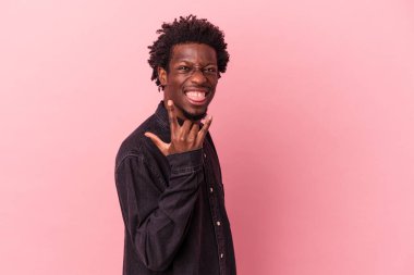 Pembe arka planda izole edilmiş genç Afrikalı Amerikalı parmaklarıyla kaya hareketi gösteriyor.