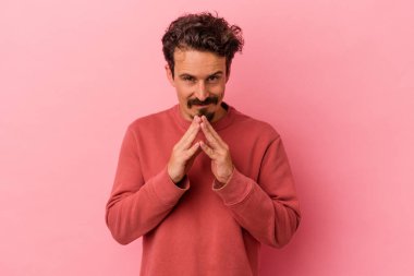 Kafkasyalı genç bir adam pembe arka planda izole edilmiş bir plan yapıyor, bir fikir kuruyor..