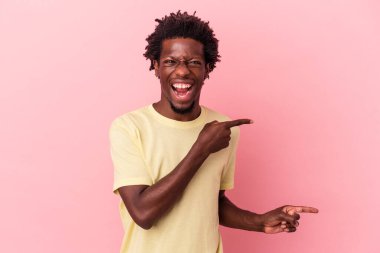 Genç Afrikalı Amerikalı bir adam pembe arka planda izole edilmiş, işaret parmaklarıyla fotokopi alanını işaret ederek heyecan ve arzusunu ifade ediyor..