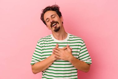 Pembe arka planda izole edilmiş genç beyaz bir adam, dostane bir ifadeye sahip, avuçlarını göğsüne bastırıyor. Aşk konsepti.