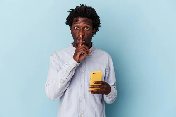 年轻的非洲裔美国人 手持蓝色背景的手机 保守秘密或要求沉默 — 图库照片