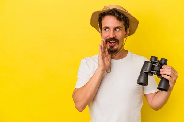 Young Caucasian Man Holding Binoculars Isolated Yellow Background Saying Secret — 图库照片