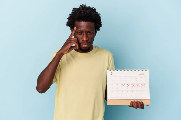 Jonge Afro Amerikaanse Man Houdt Kalender Geïsoleerd Blauwe Achtergrond Wijzende — Stockfoto