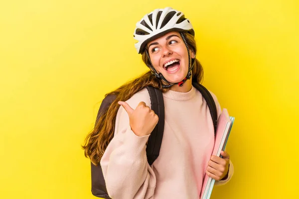 若いですCaucasian学生女性身に着けていますAバイクヘルメット隔離上の黄色の背景点とともに親指指離れて 笑いと屈託のない — ストック写真