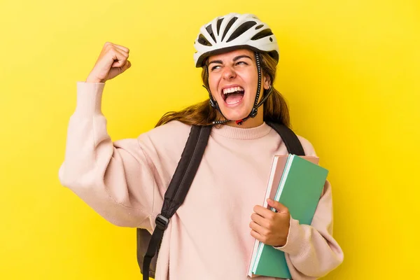 勝利の後に拳を上げ黄色の背景に隔離された自転車のヘルメットを身に着けている若い白人学生の女性 勝者の概念 — ストック写真