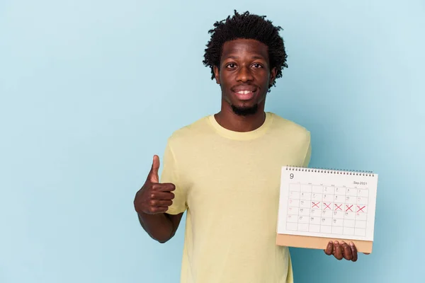 Jonge Afrikaanse Amerikaanse Man Houden Kalender Geïsoleerd Blauwe Achtergrond Glimlachen — Stockfoto