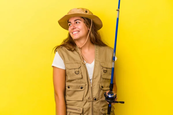 年轻的高加索女渔民手握一根黄色背景的钓竿 面带微笑 愉快地望着旁边 — 图库照片