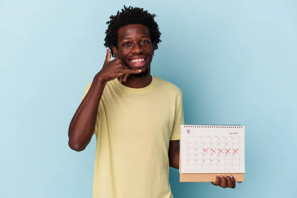 Jonge Afro Amerikaanse Man Houdt Kalender Geïsoleerd Blauwe Achtergrond Toont — Stockfoto