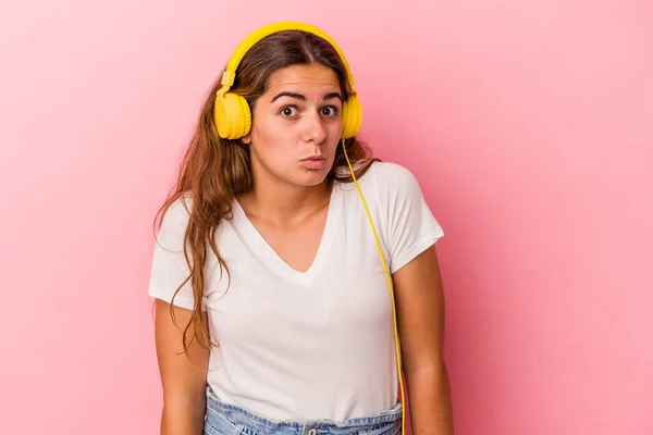 Young Caucasian Woman Listening Music Isolated Pink Background Shrugs Shoulders — Φωτογραφία Αρχείου