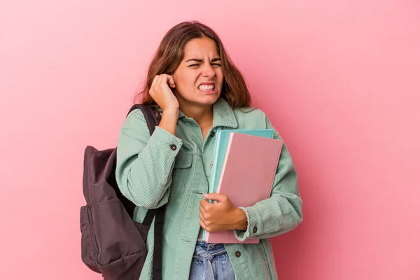 若いですCaucasian学生女性保持本隔離上のピンクの背景カバー耳で手 — ストック写真