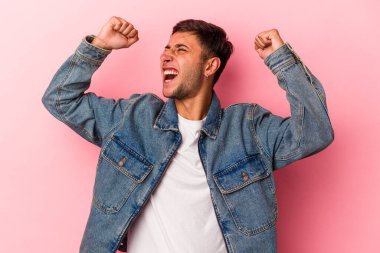 Sarı arka planda izole edilmiş beyaz dövmeli genç bir adam zaferden sonra yumruğunu kaldırıyor, kazanan konsept.