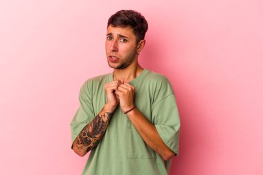 Sarı arka planda izole edilmiş dövmeleri olan genç beyaz bir adam korkmuş ve korkmuş..