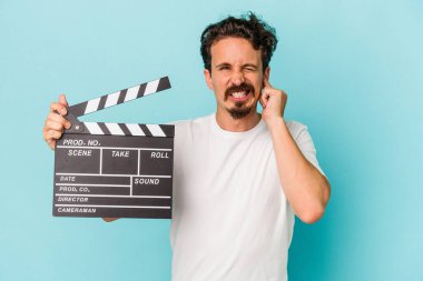 Elinde klaket tutan beyaz bir adam mavi arka planda izole edilmiş kulakları elleriyle kapatıyor..