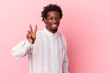 Genç Afrikalı Amerikalı bir adam pembe arka planda izole edilmiş neşeli ve kaygısız parmaklarıyla barış sembolü gösteriyor..