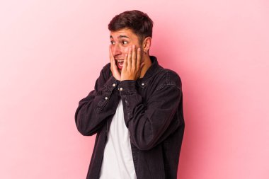 Sarı arka planda izole edilmiş dövmeleri olan genç beyaz bir adam korkmuş ve korkmuş..